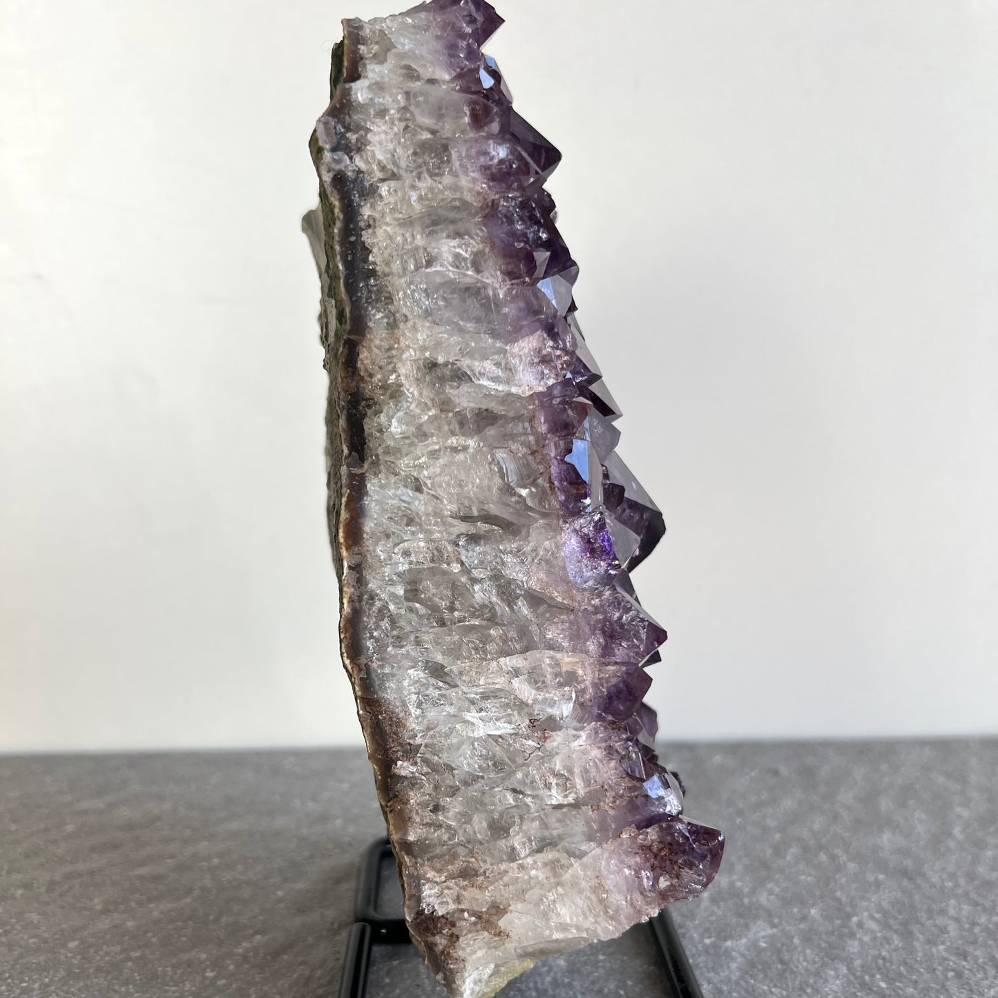 Amethyst Druse mit Ständer #4 - viele große dunkellila Kristalle - auf schwarzem Ständer - Rückseite naturbelassen - von der rohen Seite fotografiert