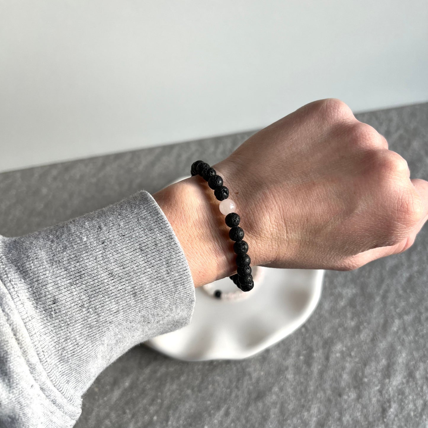 Partner-Armbandset aus 4mm Rosenquarz und Lavasteinperlen auf Tablett - Lavasteinarmband getragen