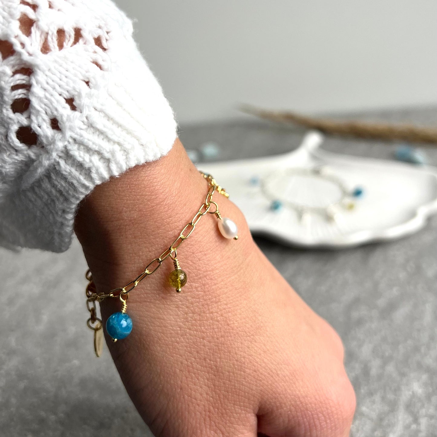 SOMMERKIND 2.0 Charm-Armkettchen in 925 Silber oder 925 Silber vergoldet - mit handgemachten Charms aus Apatit, Bergkristall, Peridot und Süßwasserperlen und einem Seepferdchenanhänger und Lelani-Charm - Nahaufnahme getragen