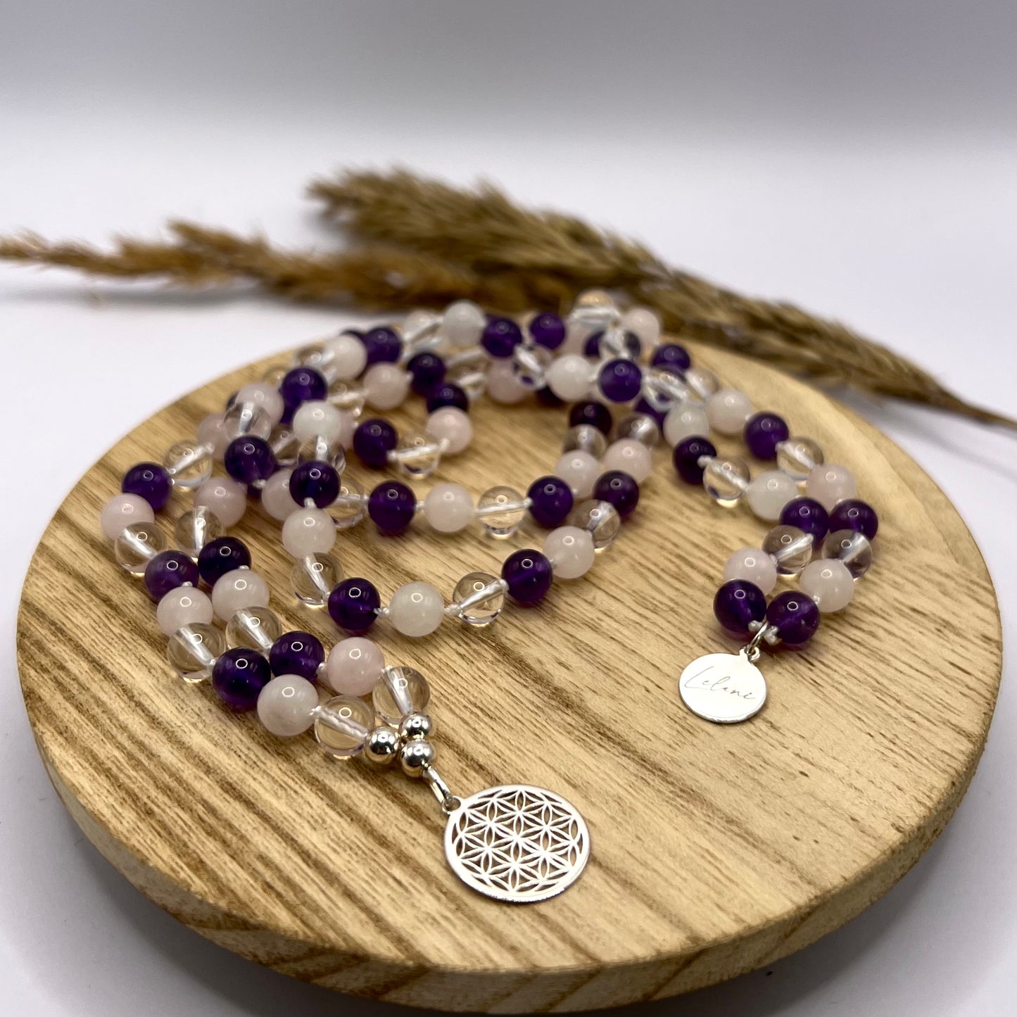 Mala Kette aus Rosenquarz, Bergkristall und Amethyst auf Holztablett