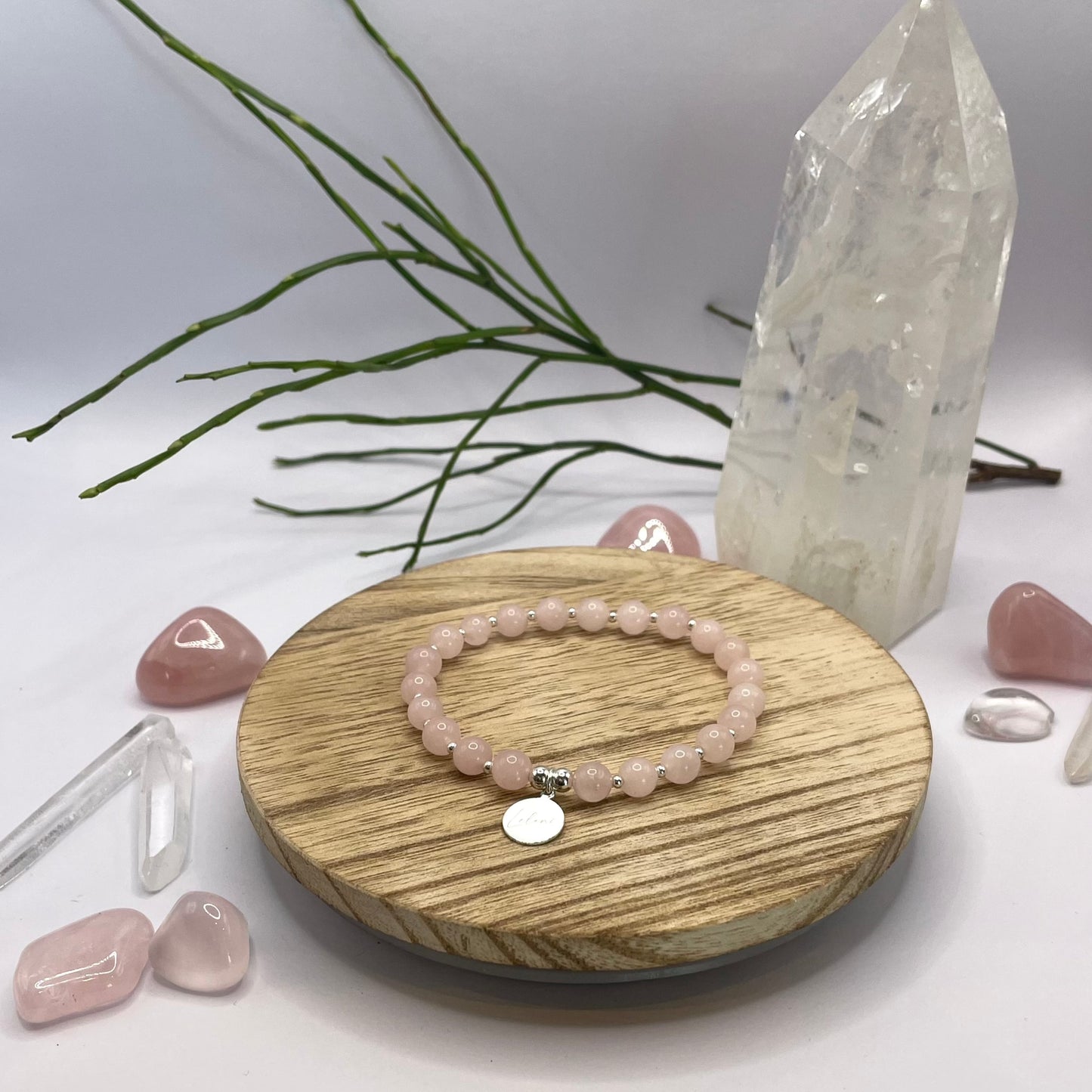 Rosenquarz Armband mit Charm und Perlen auf Holztablett