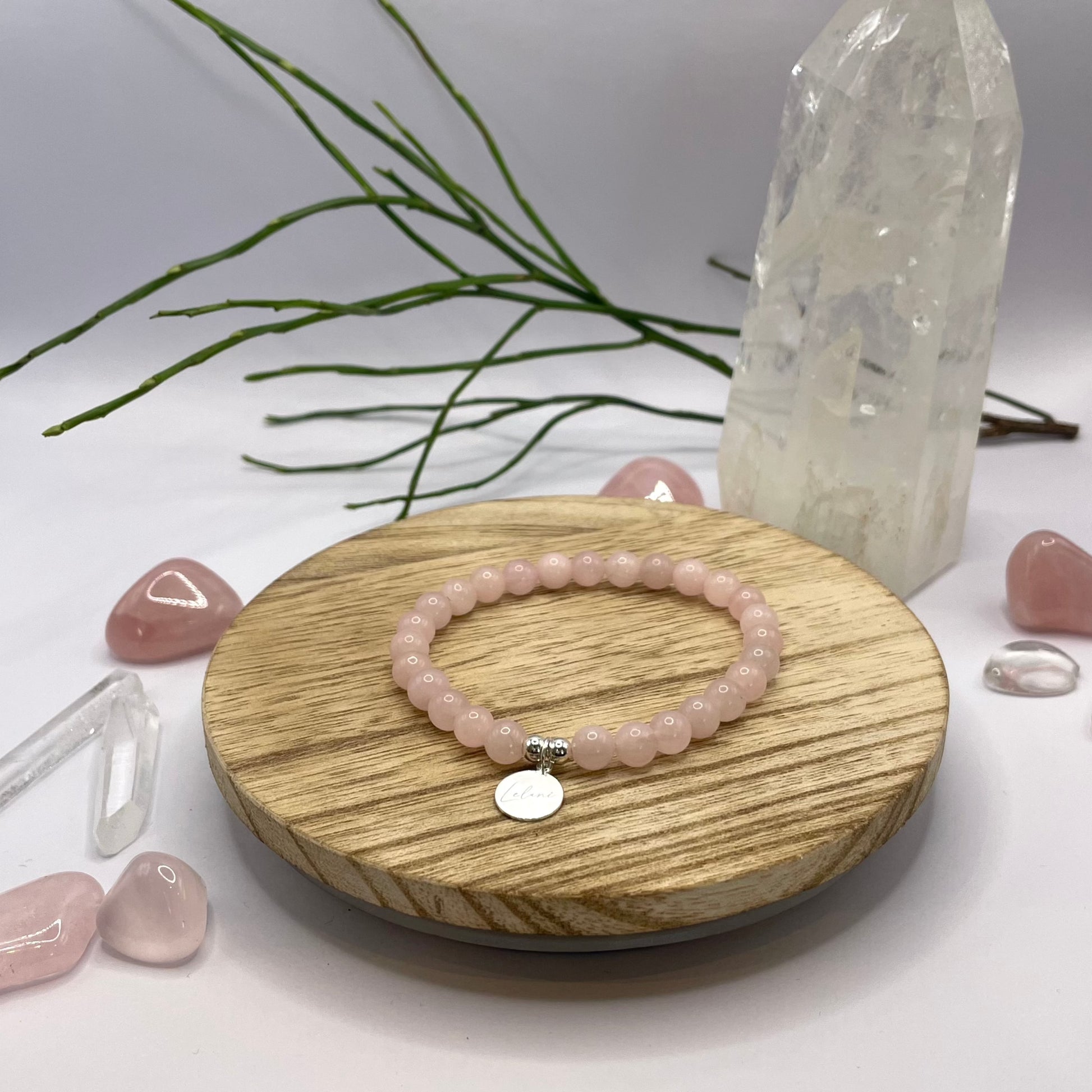 Rosenquarz Armband mit Charm auf Holztablett